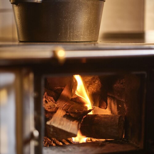 Cast iron pot on stove above burning logs | © RAPHAELGABAUER.COM