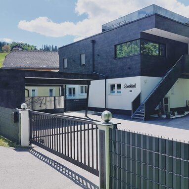 Modern two-story building with black exterior and gated entrance