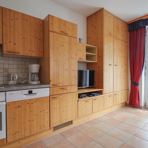 Wooden kitchen cabinets surround built-in TV and shelves.