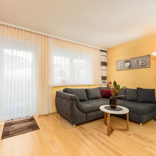 Cozy living room with gray sofa, yellow wall, and a HOME sign.