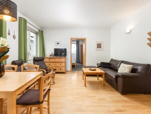 Helles Wohnzimmer mit Holzboden, Sofa und Essecke