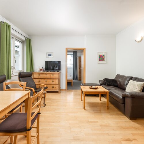 Helles Wohnzimmer mit Holzboden, Sofa und Essecke