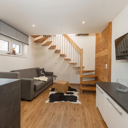 Living room with gray sofa, cowhide rug, and wooden staircase.