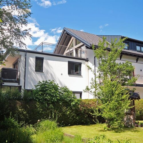 White multi-story house with balconies and garden