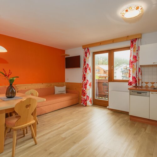 Gemütlicher Wohnbereich mit orangener Wand und Sofa; Kissen mit Lieblingsplatz.