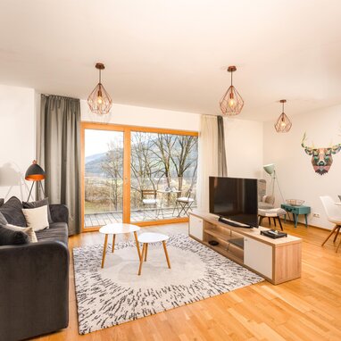 Modern living room with grey sofa, glass doors, and geometric wall art
