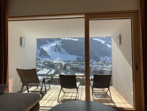Balcony with wicker chairs overlooking a snowy mountain village