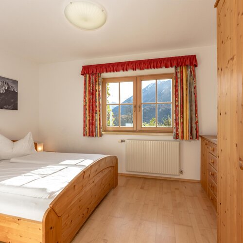 Warm wooden bed in bright alpine bedroom with mountain view
