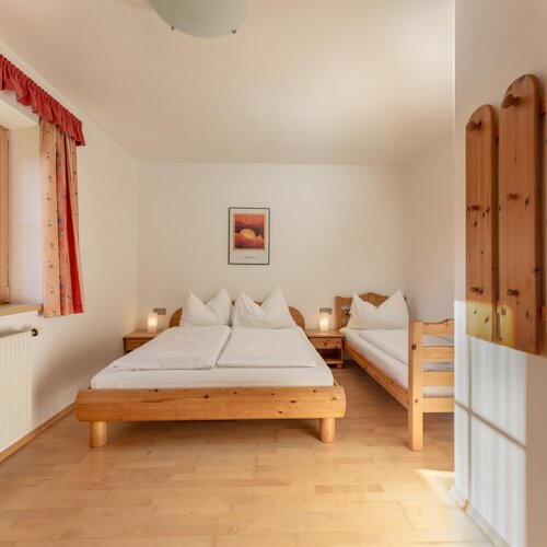 Bright room with a double bed and a single wooden bed