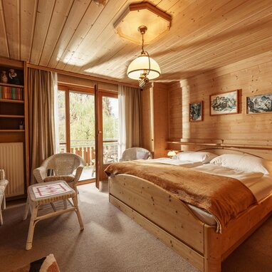 Wood-paneled bedroom with a large bed and balcony doors