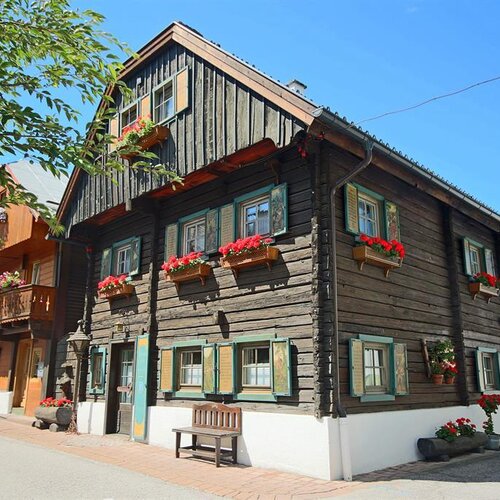 Brown wooden house with flower boxes on a sunny street