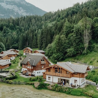 Aerial view of wooden chalets in a forested valley.