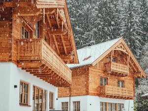 Snowy alpine wooden chalet with balconies and pine trees