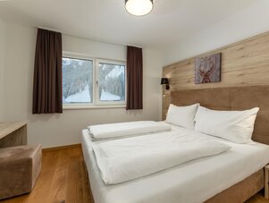 Double bed in modern hotel room with wood-paneled wall