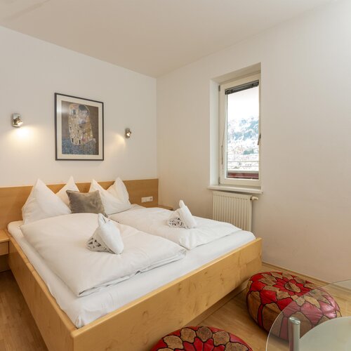 Large double bed with white linens in bright room with window