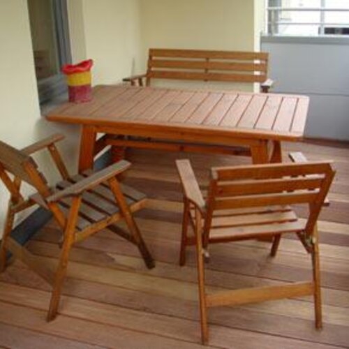Wooden outdoor dining set on balcony with four chairs.