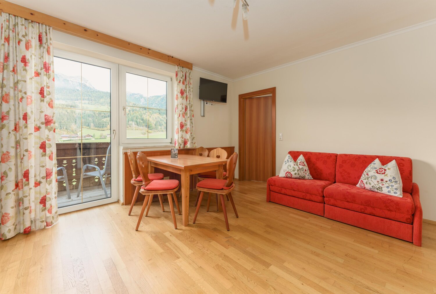 Wohnzimmer mit rotem Sofa und Esstisch, Blick auf Berge