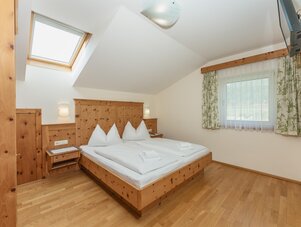 Helles Holzschlafzimmer mit Dachfenster und Doppelbett