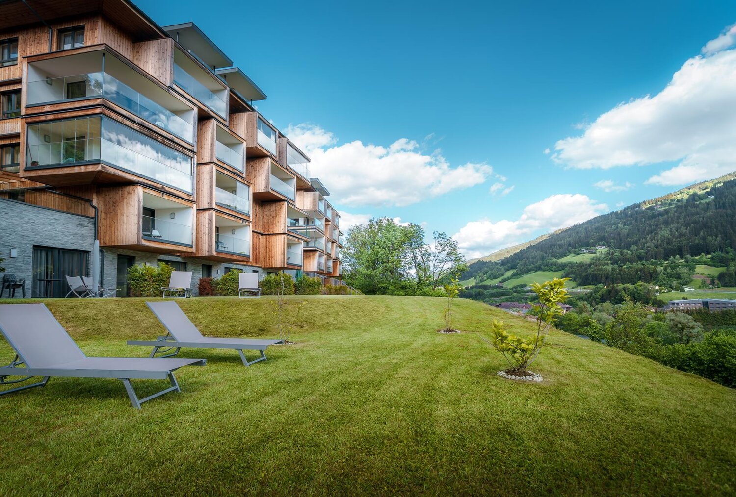 Modern wooden apartment building with balconies on grassy hillside