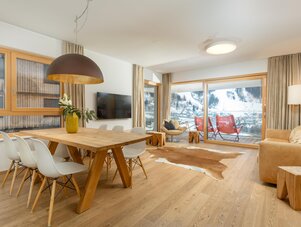Bright open living and dining area with wooden furniture and mountain view.