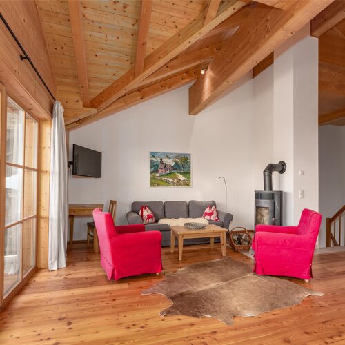 Cozy wood-paneled living room with red armchairs and fireplace