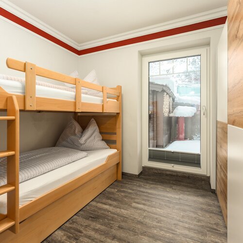 Schlafzimmer mit Holzbunkbetten und großer Glastür