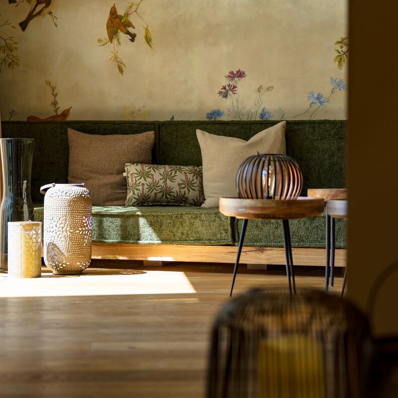 Gemütliches Wohnzimmer mit grünem Sofa, Kissen und Laternen