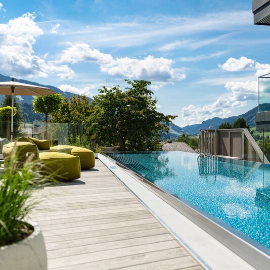 Dachterrassen-Pool mit Lounge-Sesseln und Bergblick