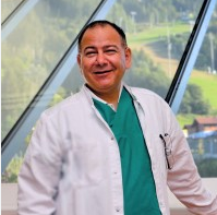 Lächelnder männlicher Arzt im weißen Kittel drinnen