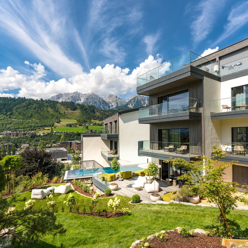 Modern residential building with glass balconies and landscaped garden.