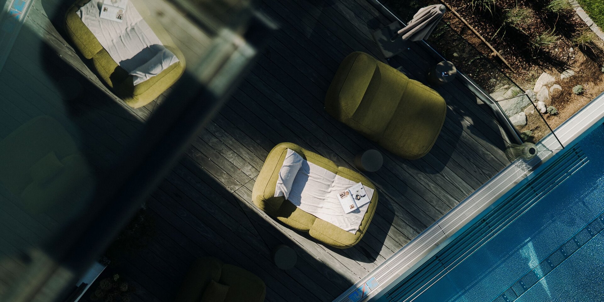 Aerial view of poolside deck with green lounge chairs and magazines