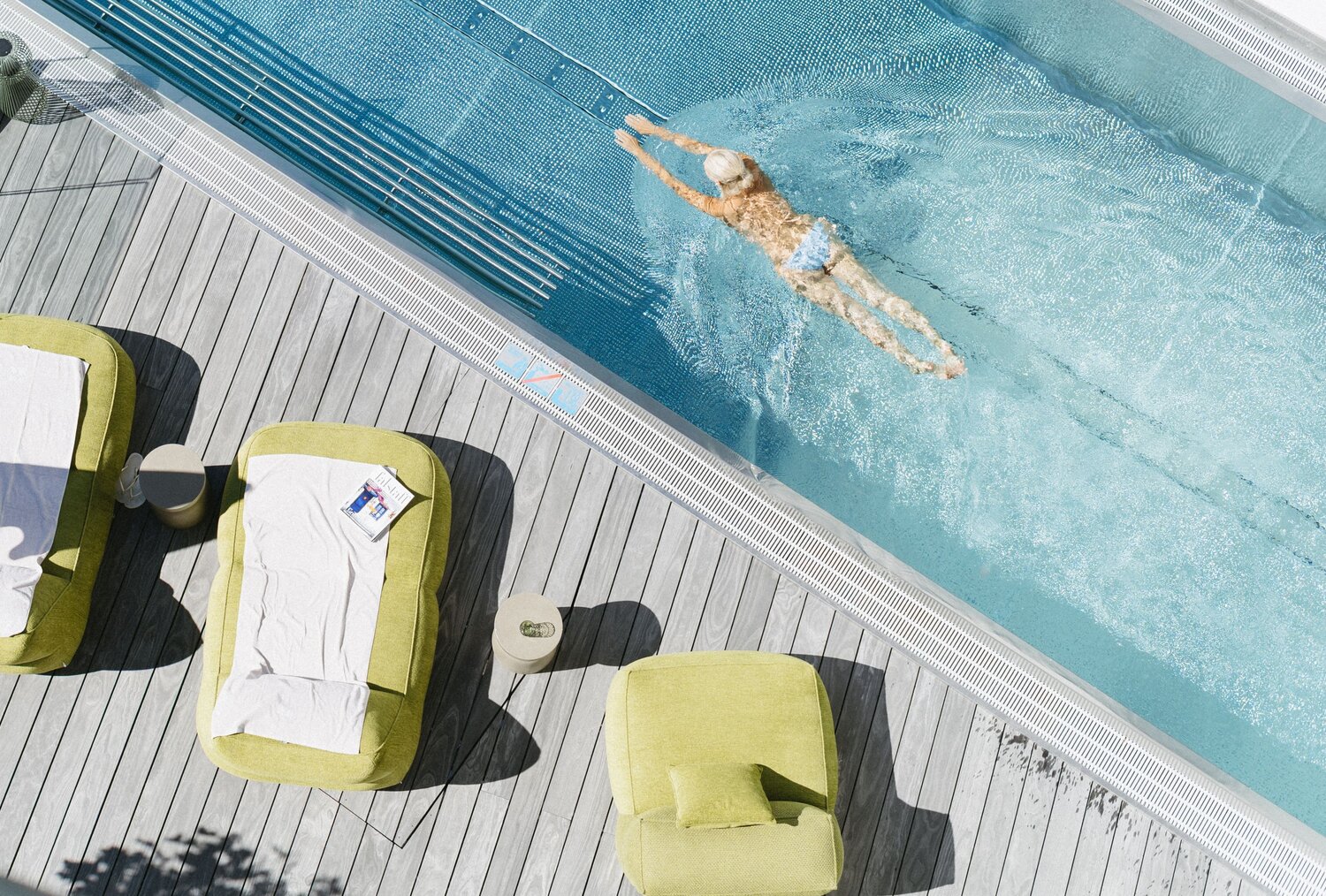 Aerial view of a poolside deck with green loungers