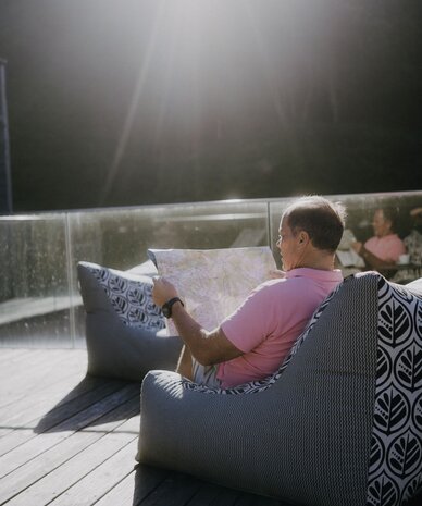 Man in pink polo reading a map on an outdoor deck chair