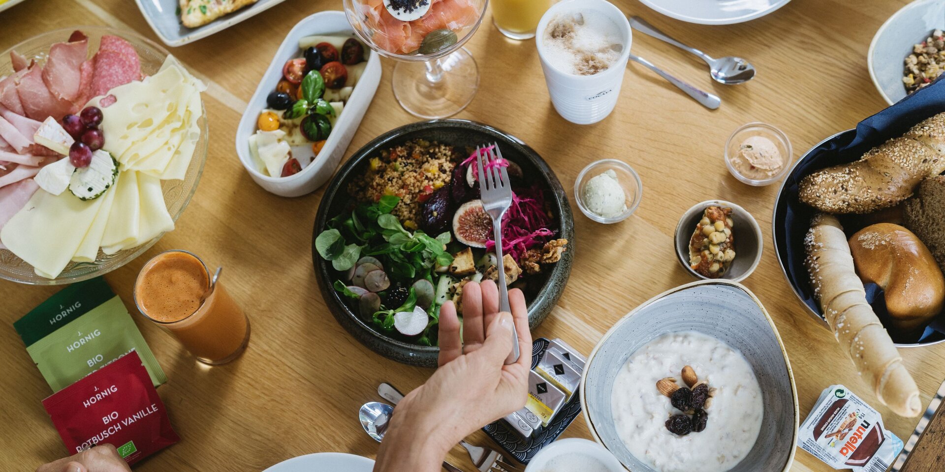 Overhead view of varied breakfast spread with cheese, bread, salad