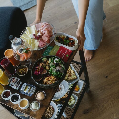 Person arranging a colorful array of dishes on a cart.