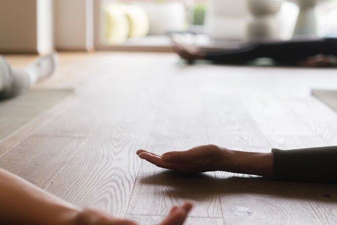 Zwei Hände erreichen sich auf dem Holzboden drinnen.