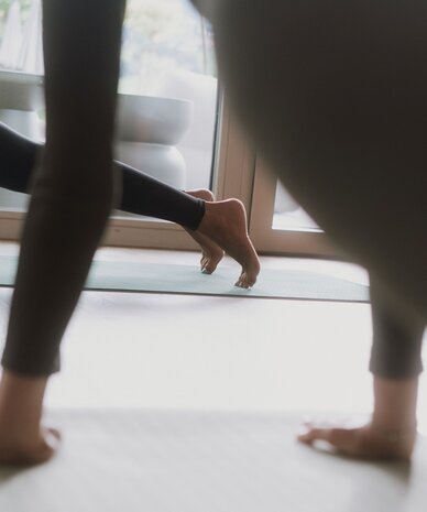 Zwei Personen machen Yoga auf Matten am Fenster