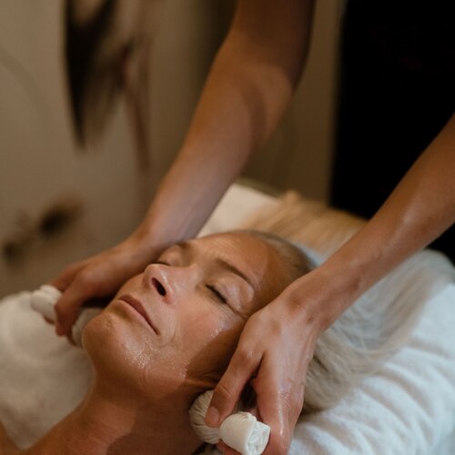 Frau erhält Gesichtsmasage im Spa, liegend