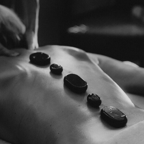 Rückenmassage mit heißen Steinen entlang der Wirbelsäule