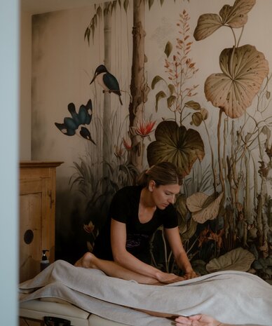 Therapist giving massage to client in treatment room