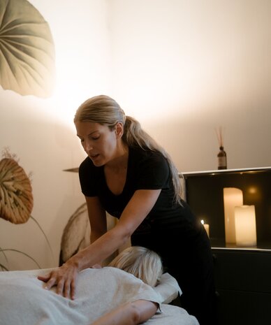 Massageprofi führt Rückenmassage bei liegender Person aus