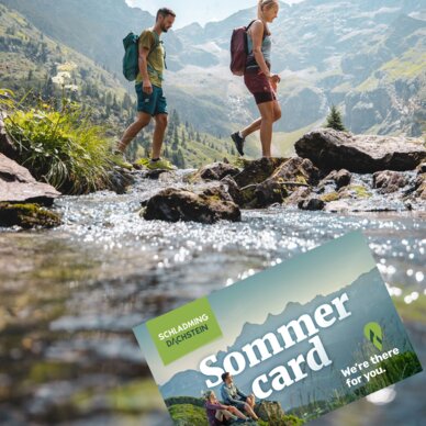Two hikers cross a rocky stream in alpine valley; Sommer card overlay.